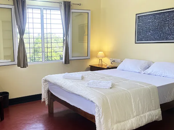 Guest room at Surya Villa Auroville with queen-size bed, natural light, and peaceful ambiance